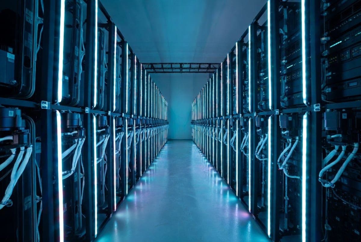 Rows of server racks in a modern data center with blue cooling lights, representing AI infrastructure hardware