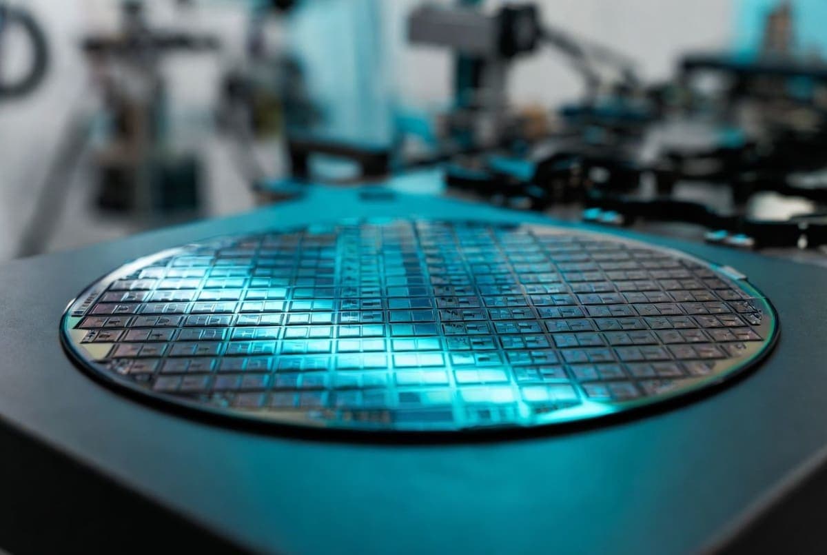 Polished silicon wafer covered in processor dies under cool blue lighting inside a semiconductor cleanroom