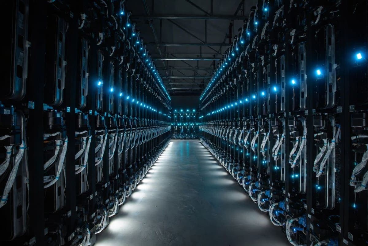 Rows of server racks in a large AI data center with blue status lighting